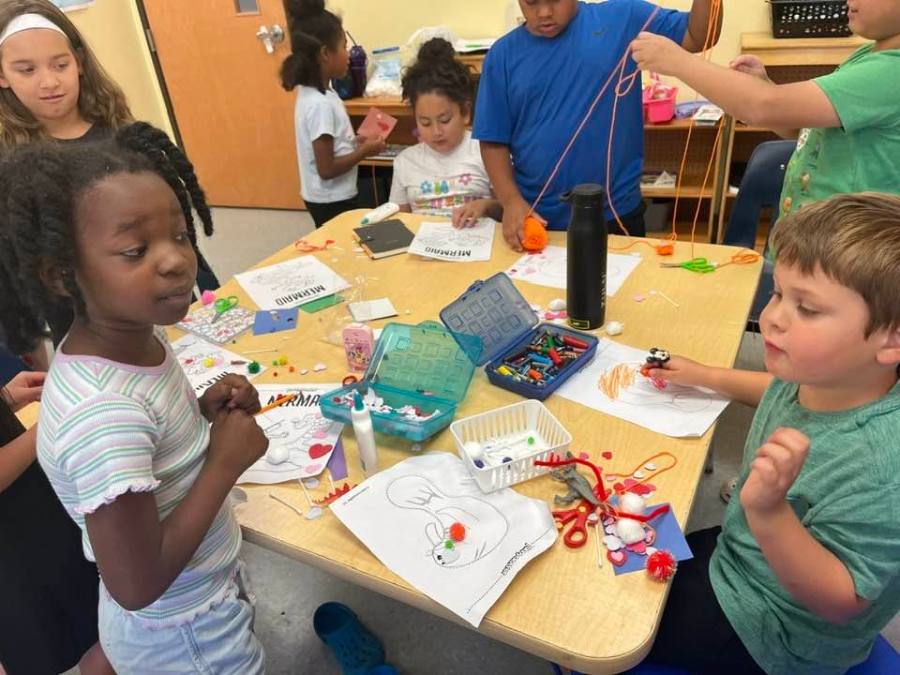 Children working on a craft project together at a classroom table