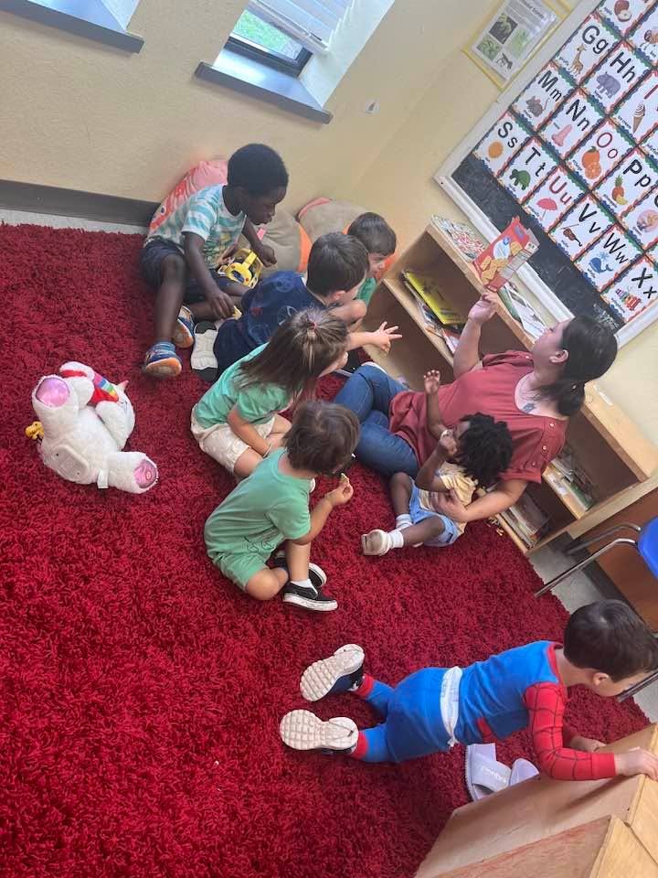 Children playing together on a red rug in a sunny classroom